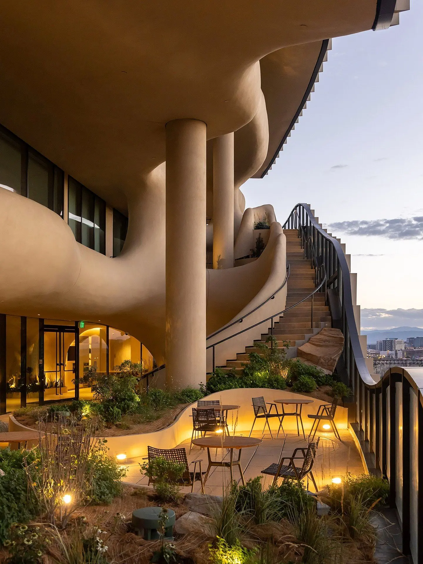 نمای ساختمان وان ریور نورث در دنور با نمای شیشه‌ای و شکاف عمیق صخره‌ای مجهز به گیاهان طبیعی و مسیر پیاده‌روی عمودی.