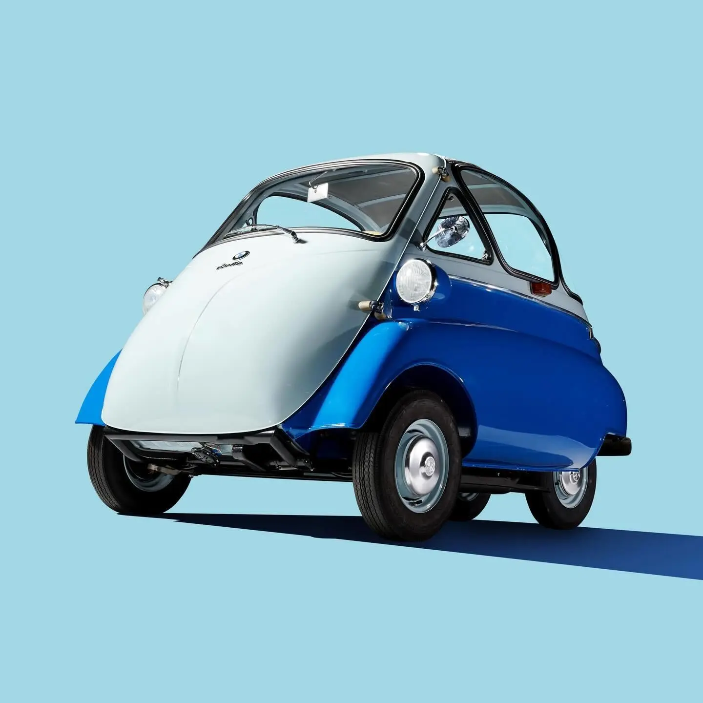 تصویر یک خودروی مینیاتوری کلاسیک به نام BMW Isetta (ب‌ام‌و ایزتا) که به دلیل طراحی گرد و کوچک خود به "خودروی حبابی" (Bubble Car) مشهور است، و در دهه ۱۹۵۰ نقش کلیدی در نجات مالی شرکت ب‌ام‌و از ورشکستگی ایفا کرد.