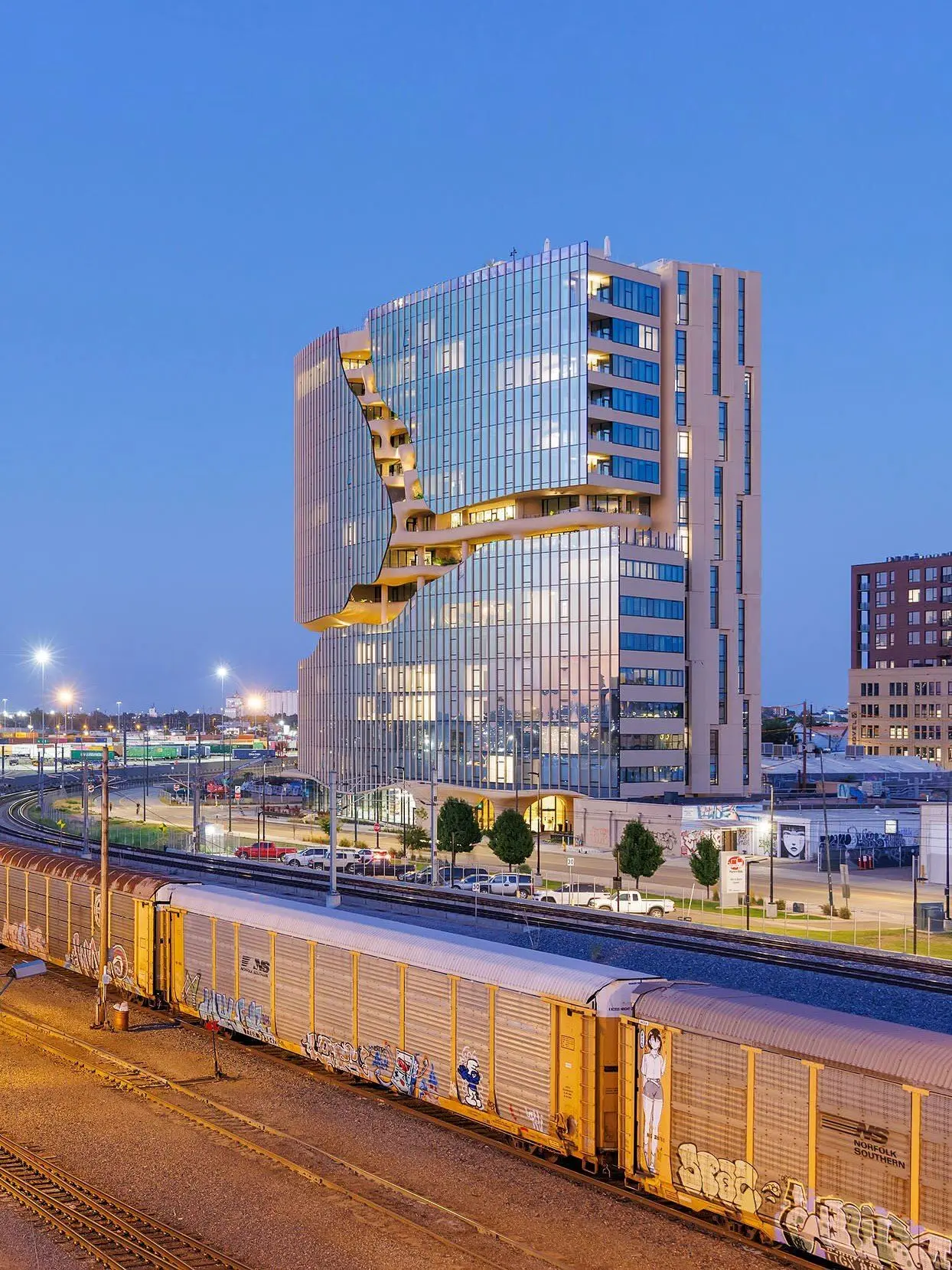 نمای ساختمان وان ریور نورث در دنور با نمای شیشه‌ای و شکاف عمیق صخره‌ای مجهز به گیاهان طبیعی و مسیر پیاده‌روی عمودی.