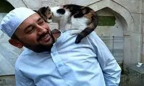 تصاویر بالا رفتن یک گربه روی دوش امام اقامه نماز /واکنش امام جماعت را ببینید