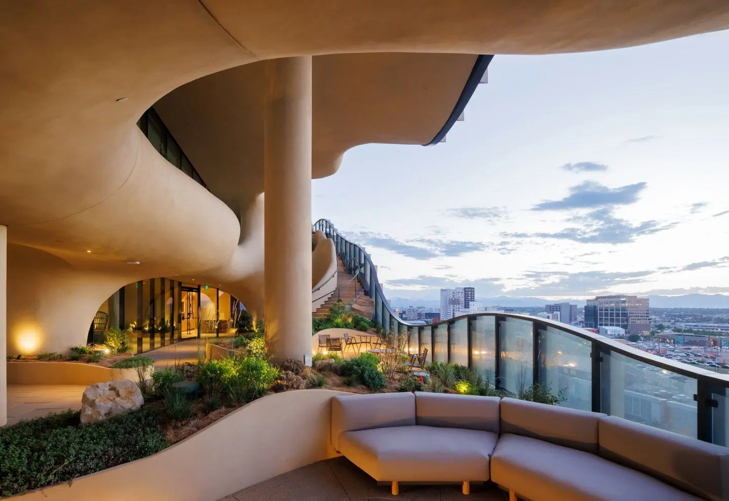 نمای ساختمان وان ریور نورث در دنور با نمای شیشه‌ای و شکاف عمیق صخره‌ای مجهز به گیاهان طبیعی و مسیر پیاده‌روی عمودی.