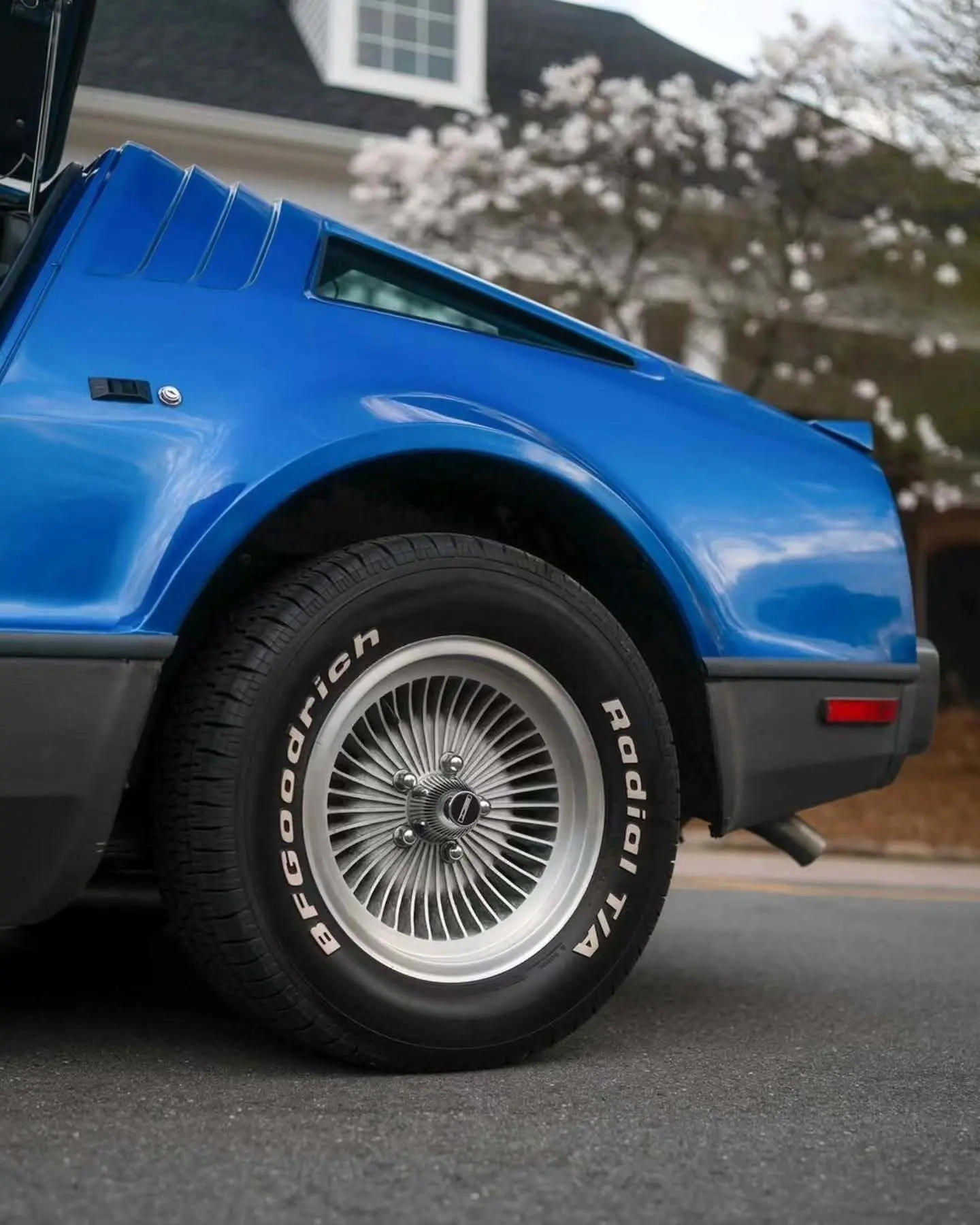 نمای جانبی خودروی کلاسیک بریکلین SV-1 با درهای باز شده رو به بالا و بدنه آکریلیک نارنجی رنگ که طراحی ایمن و آیرودینامیک آن را نشان می‌دهد.