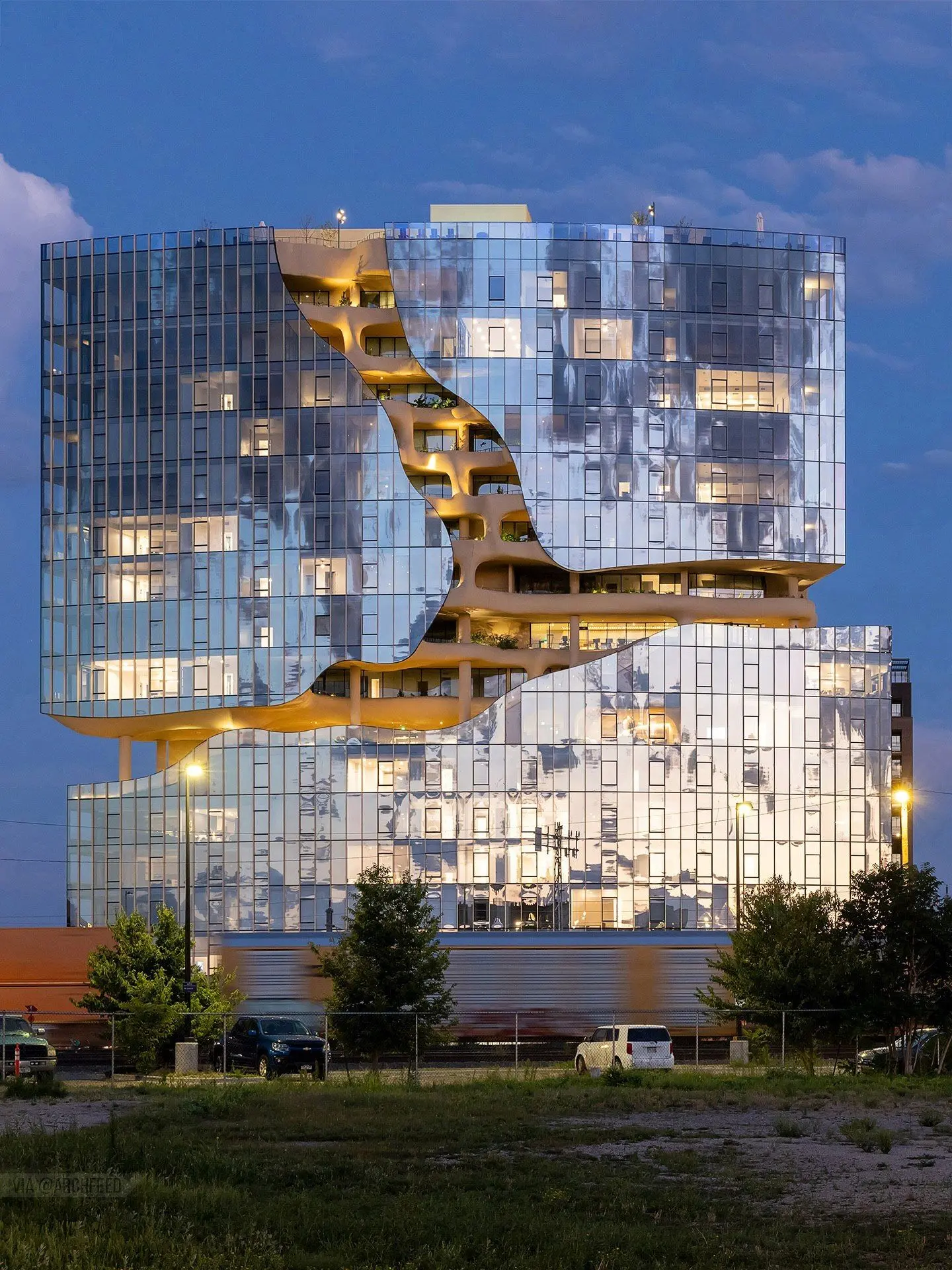 نمای ساختمان وان ریور نورث در دنور با نمای شیشه‌ای و شکاف عمیق صخره‌ای مجهز به گیاهان طبیعی و مسیر پیاده‌روی عمودی.