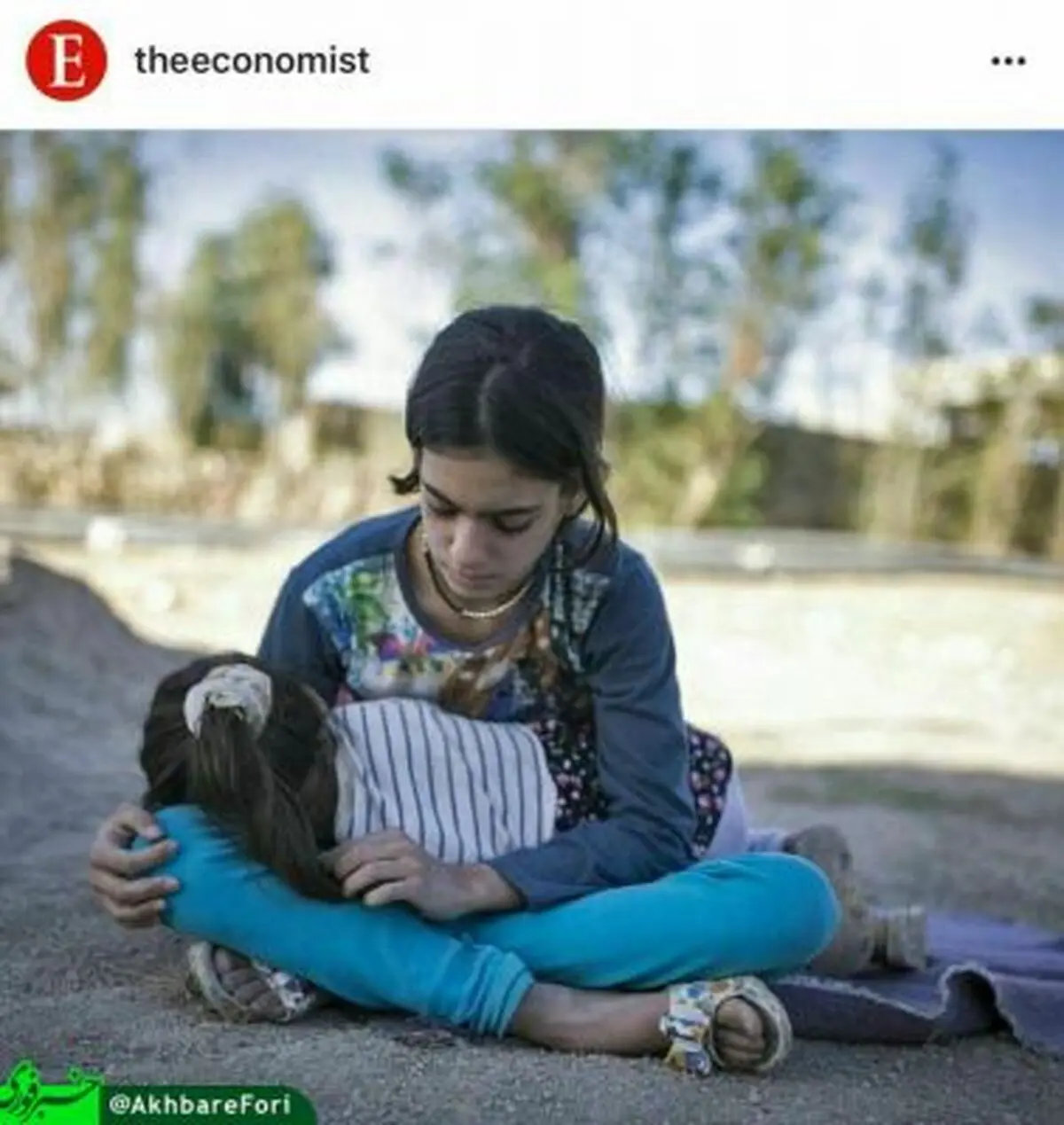 دختر بچه‌ای که خواهر خردسالش را در سرپل ذهاب به آغوش گرفته است + تصویر