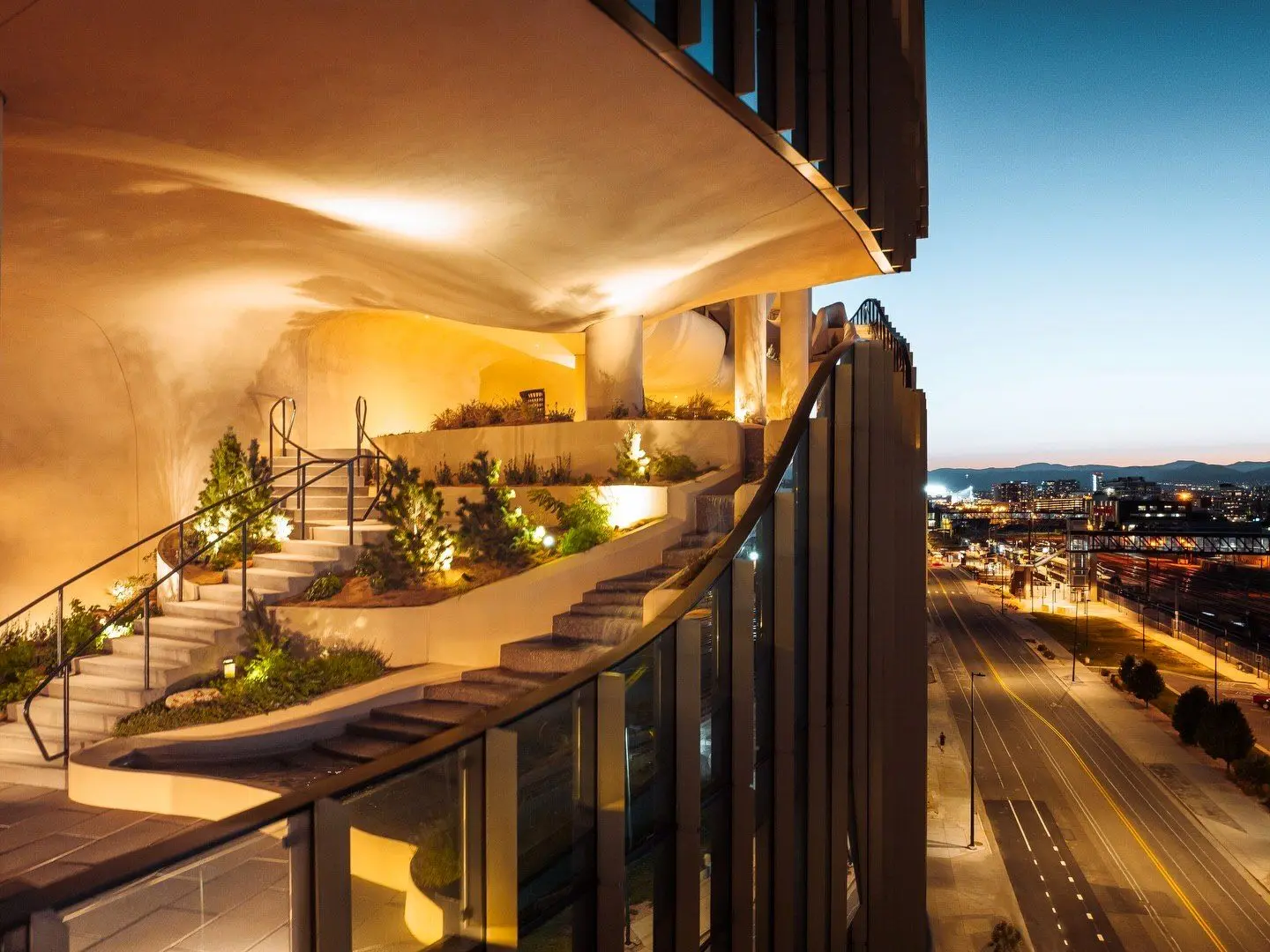 نمای ساختمان وان ریور نورث در دنور با نمای شیشه‌ای و شکاف عمیق صخره‌ای مجهز به گیاهان طبیعی و مسیر پیاده‌روی عمودی.