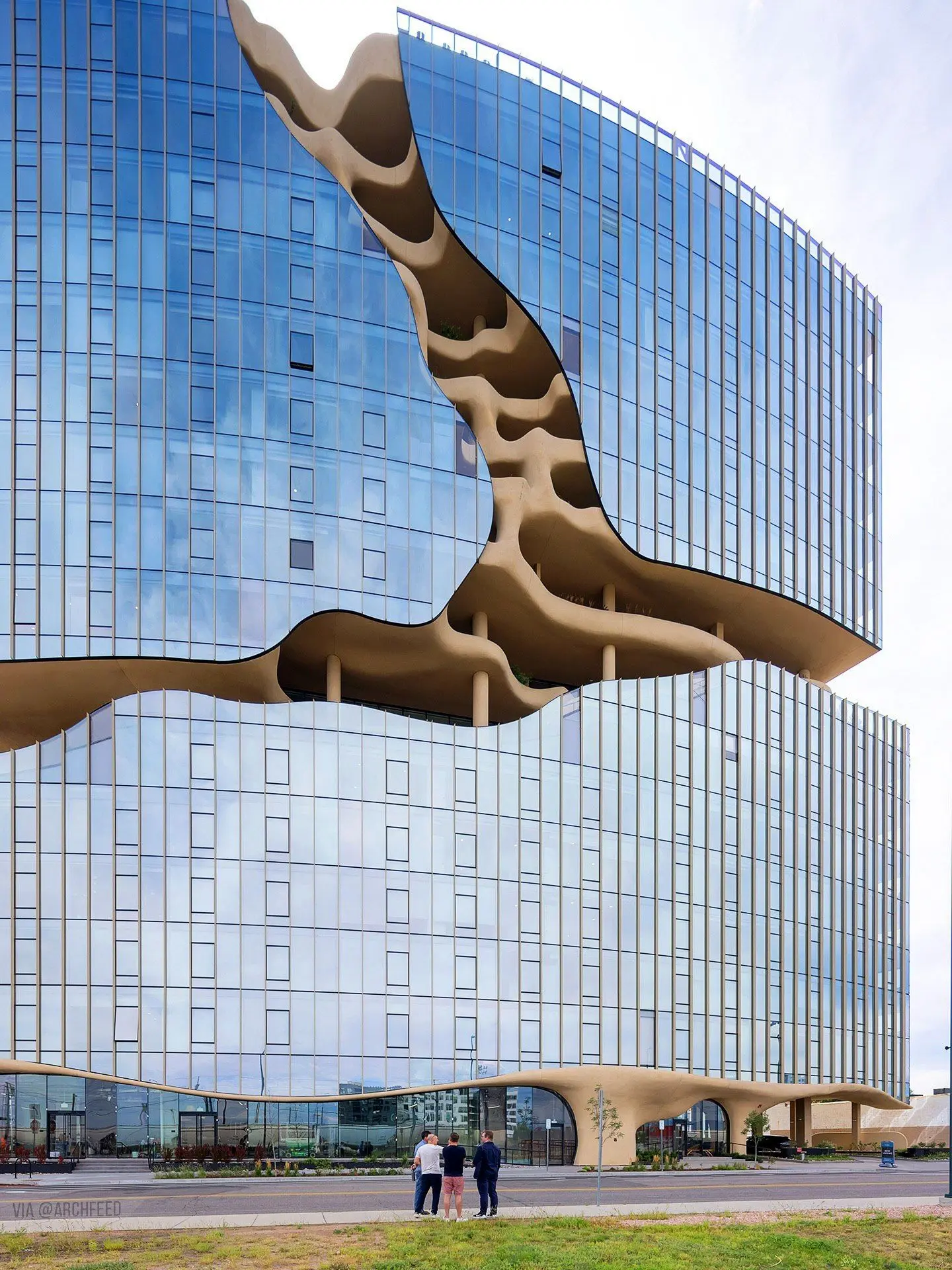 نمای ساختمان وان ریور نورث در دنور با نمای شیشه‌ای و شکاف عمیق صخره‌ای مجهز به گیاهان طبیعی و مسیر پیاده‌روی عمودی.