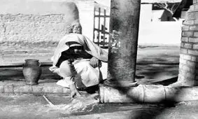 پیرمرد تهرانی در حال پر کردن کوزه از آب چاه؛ سال ۱۳۴۰